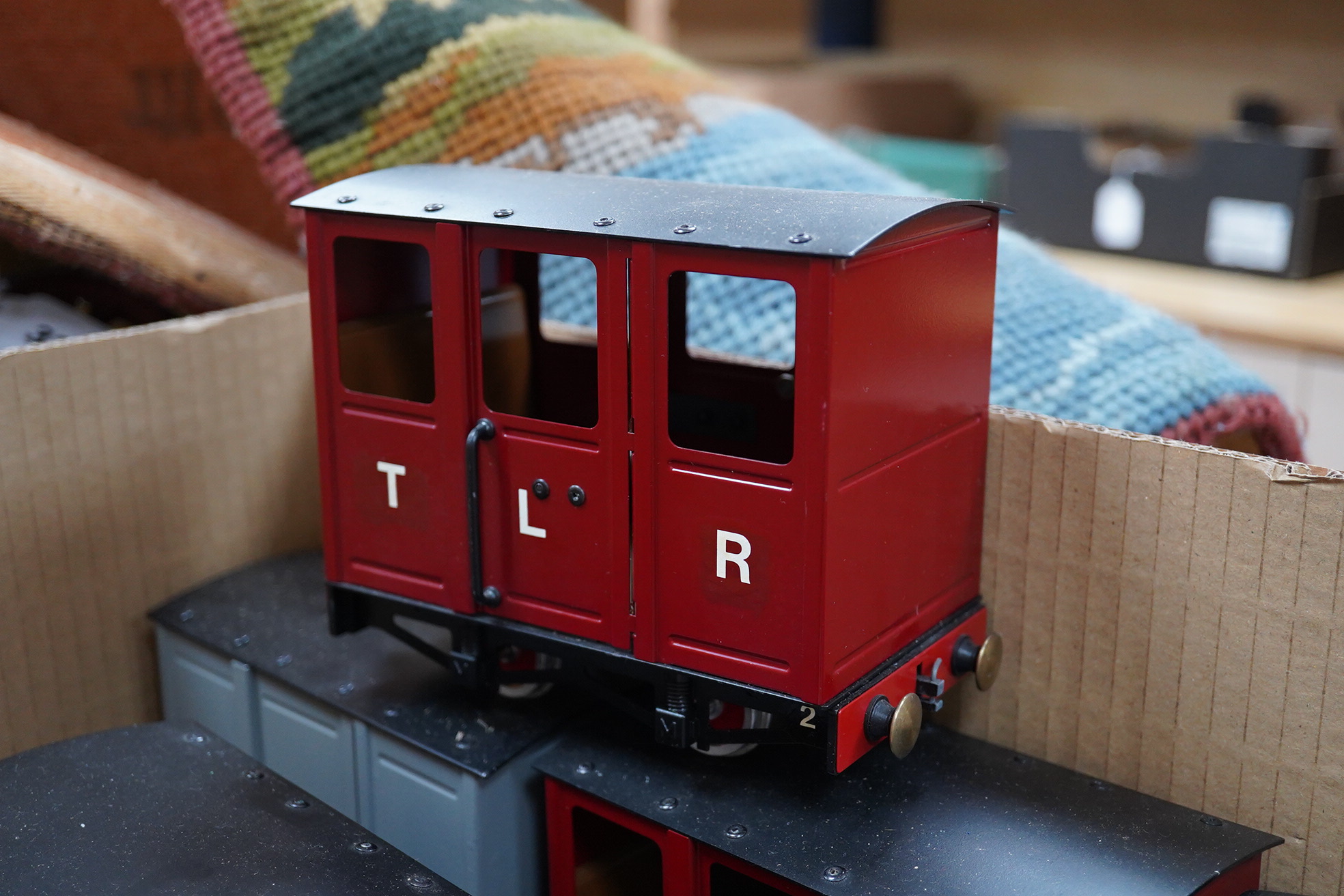 Nine Mamod narrow gauge coaches and freight wagons running on 32mm rails, comprising; three maroon painted 4-wheel coaches, two box vans, a guard’s van, two open wagons and a flatbed with log load
